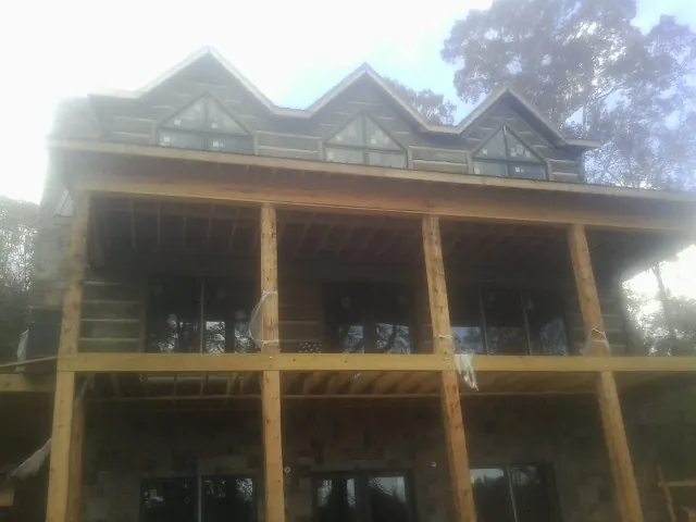 Dormers and porch framing on a large log home under construction — Roof Coating work by our crew in Continental