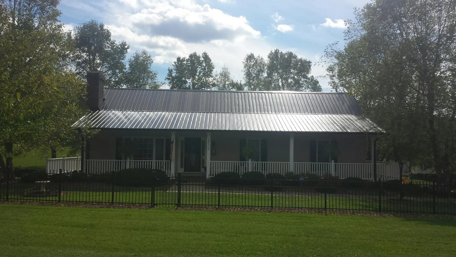 Gray metal roof on a brick ranch with a full width front porch — Gutter Guard Installation work by our crew in Continental