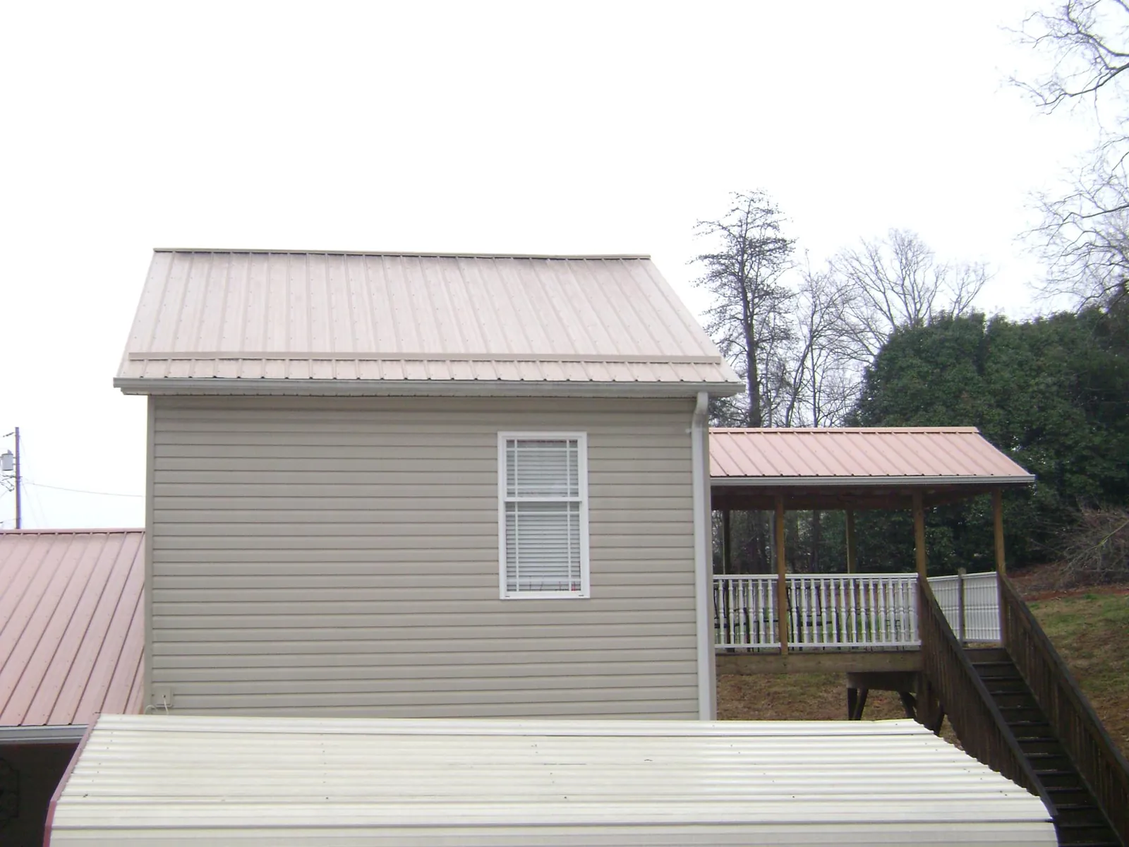 Tan metal roofs on a two story addition and attached porch, from a Roof Replacement job in Continental