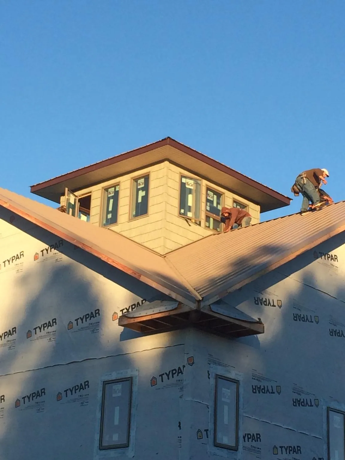 Roofers working around a rooftop cupola on a new metal roof at sunset — Roof Waterproofing in Continental by Roofing Brothers